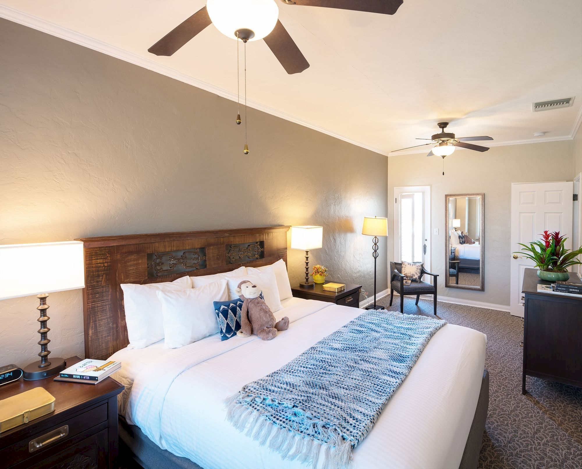 Bright bedroom with a large bed, bedside lamp, and ceiling fans with hanging lights.